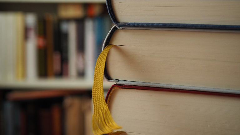 Close up of stack of books with yellow ribbon page marker in middle book