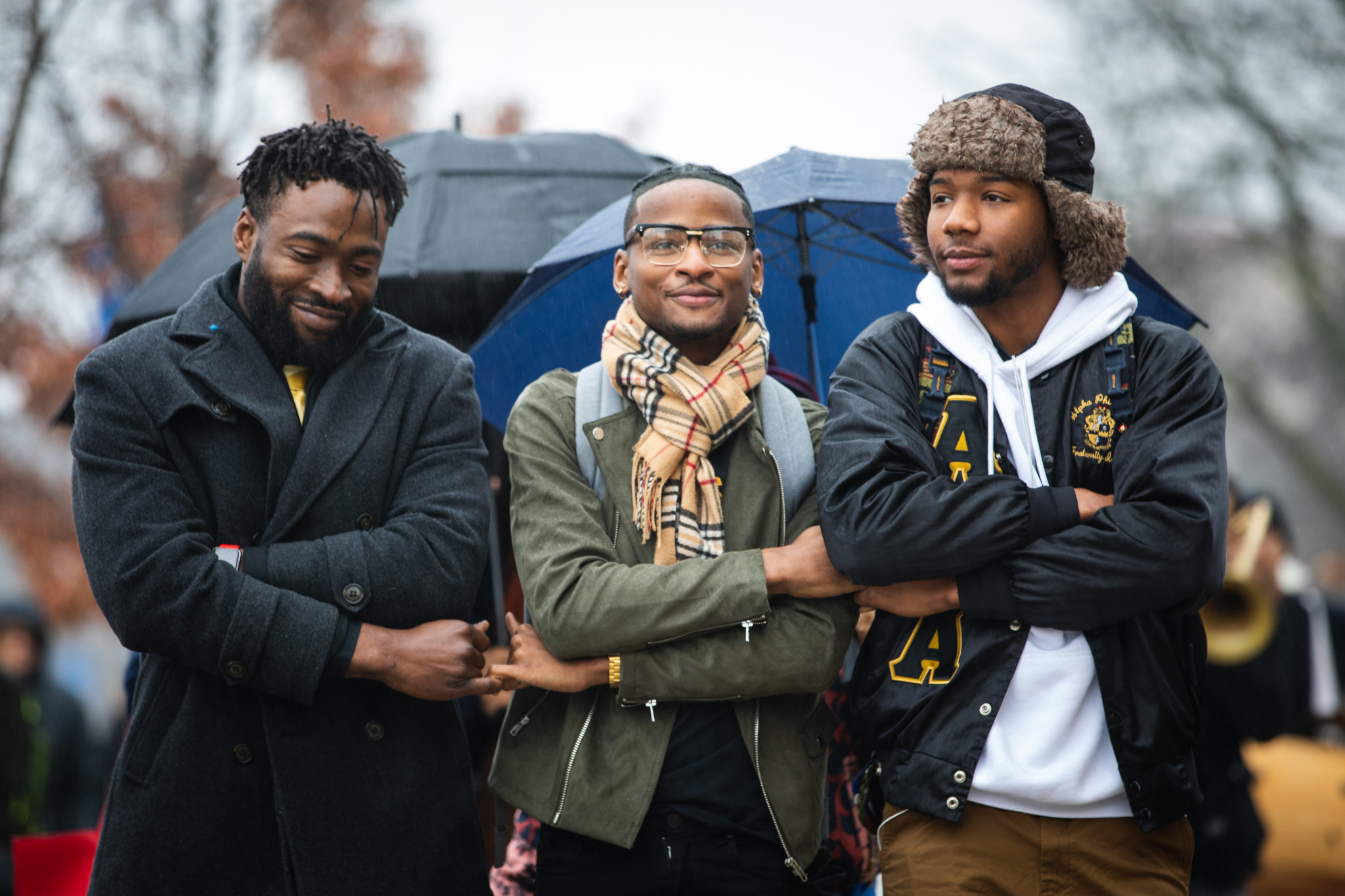 Three Black students locking arms to show unity.